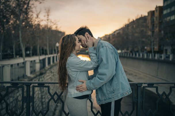 Νέοι εραστές φιλί στο όμορφο ηλιοβασίλεμα. Ημέρα του Αγίου Βαλεντίνου - Φωτογραφία, εικόνα