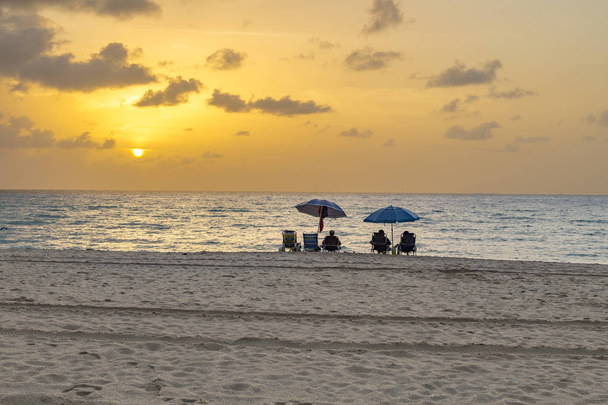 les gens profitent du coucher de soleil sur la plage sud
 - Photo, image