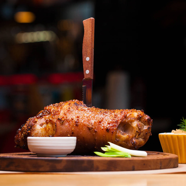 Restaurant dish - large baked pork knuckle on a wooden tray - Foto, Imagem