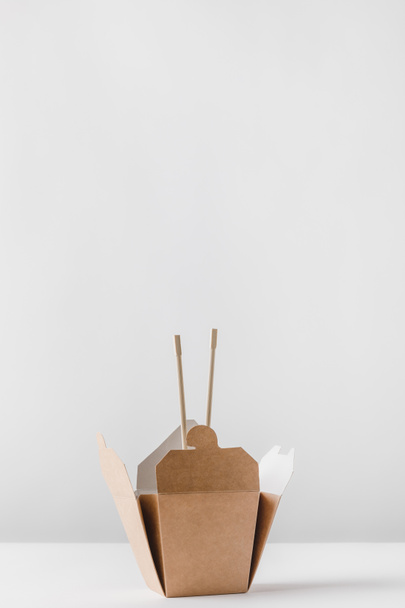 Nudelbox mit Stäbchen auf weißem Tisch - Foto, Bild