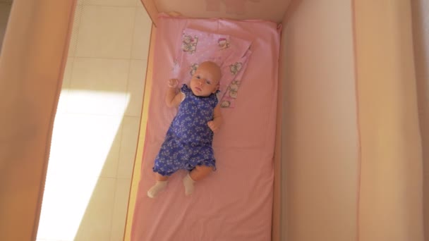 Quiet baby girl in playpen - Materiał filmowy, wideo