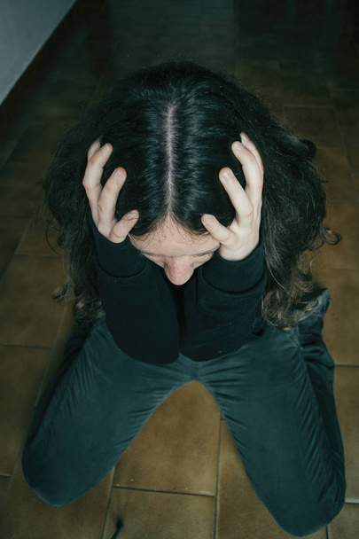 smutna dziewczyna klęcząc na podłodze z rękami na głowie - Zdjęcie, obraz
