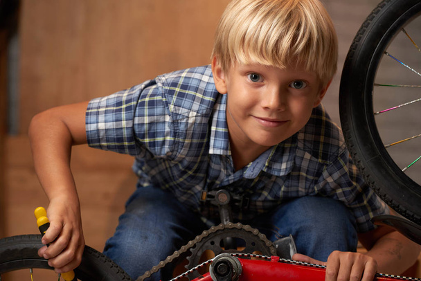 Portrait of smiling boy repairing his bike - Photo, Image