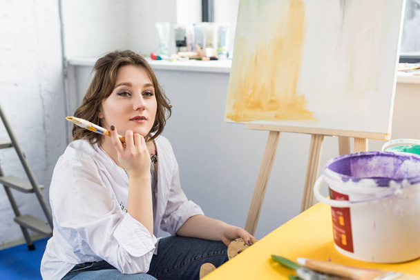 Fiatal kreatív lány álmodik a festőállvány a könnyű stúdió - Fotó, kép