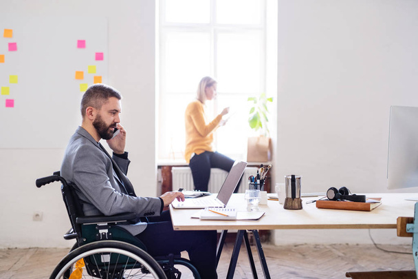Two business people with wheelchair in the office. - Fotografie, Obrázek