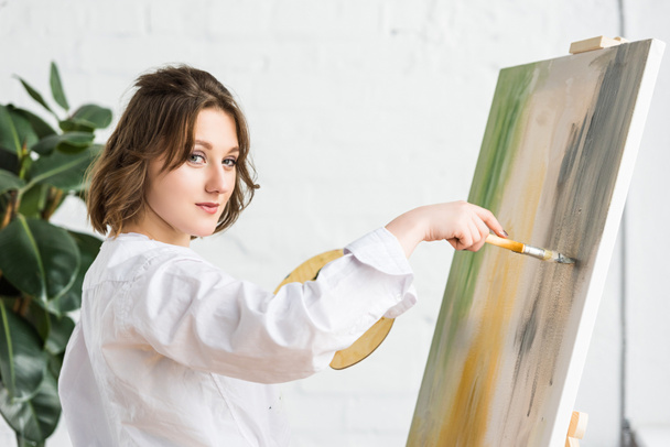 Nuori innoittamana tyttö työskentelee maalausteline valossa studio
 - Valokuva, kuva