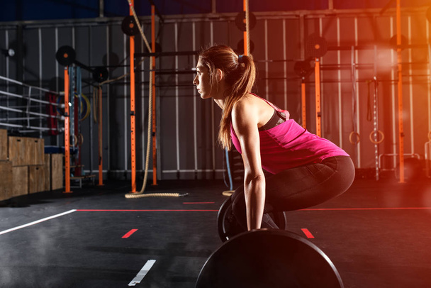 Determined athletic girl working  out at the gym with a barbell - Photo, Image