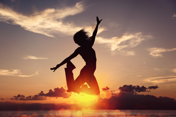 Silhouette of happy joyful woman jumping and having fun at the beach against the sunset. Concept of freedom and leisure vacation - Фото, зображення