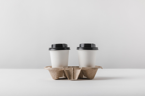 two coffee in paper cups in cardboard tray on tabletop - Fotoğraf, Görsel