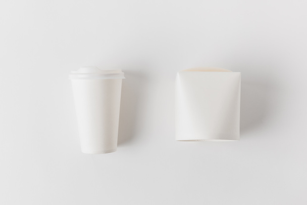top view of coffee in paper cup and noodles box on white surface - Photo, Image