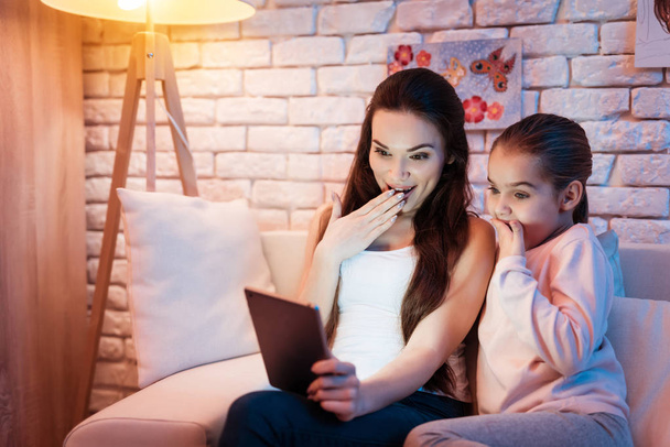Mother and little daughter speaking with father on tablet at night at home. - 写真・画像
