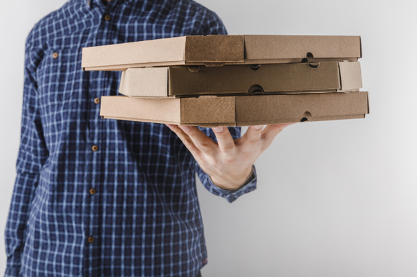 cropped image of courier holding pizza boxes on one hand isolated on white - Fotoğraf, Görsel