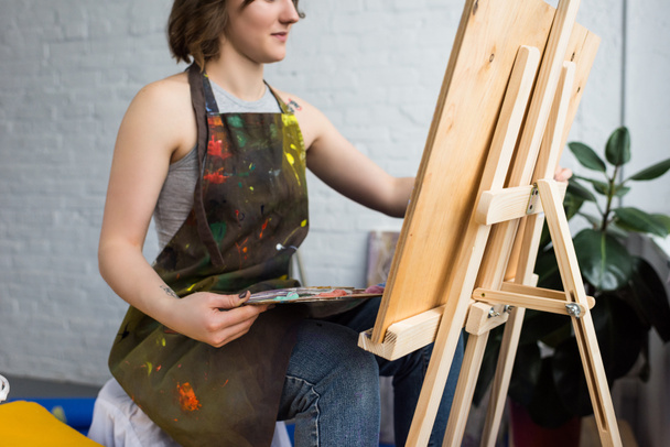 Artistieke meisje schilderij op doek in lichte studio - Foto, afbeelding
