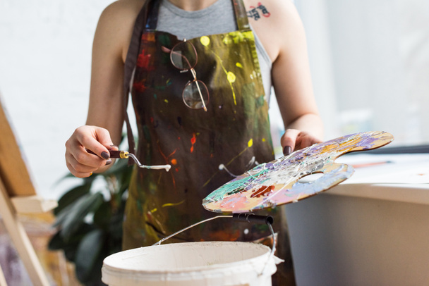 Close-up view of young inspired girl working with painting knife and palette in light studio - 写真・画像