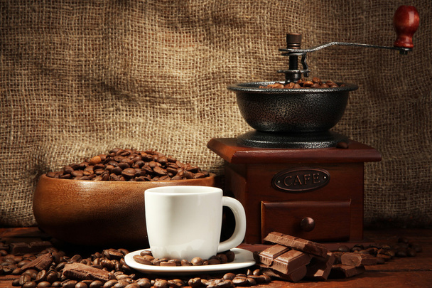 Coffee grinder and cup of coffee on burlap background - Fotó, kép