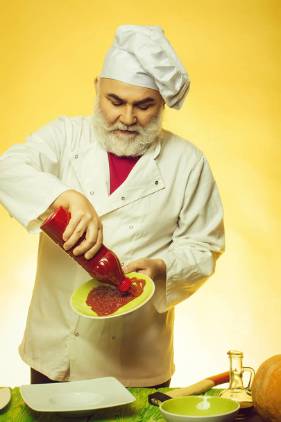Bearded cook with ketchup bottle - 写真・画像
