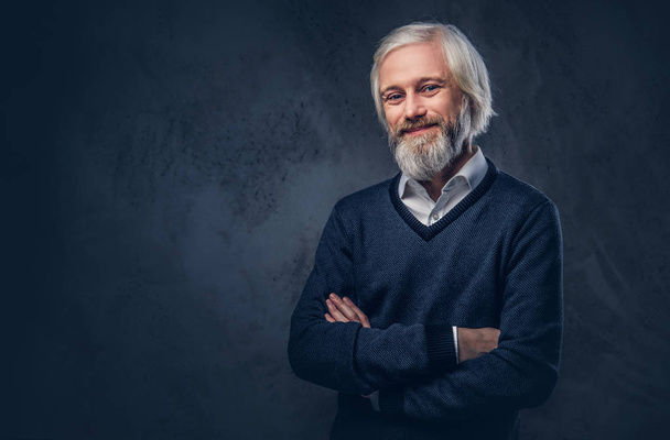 Portrait of smiling aged male with a gray beard isolated on a dark background. - Photo, Image