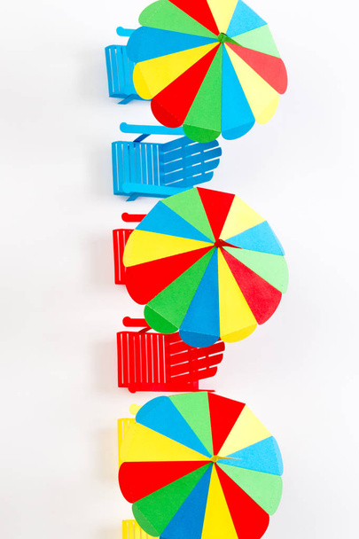 Bright umbrellas folding chairs are made of paper on a white background - 写真・画像