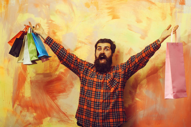 Happy bearded man shouting with colorful paper shopping bags - Photo, Image