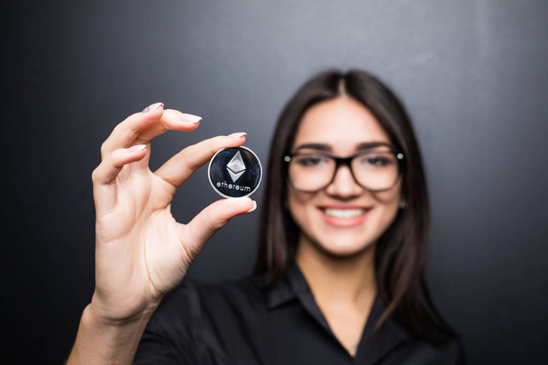 Молодих бізнес жінка в окулярах з Litecoin в руках ізольовані на чорному фоні. - Фото, зображення