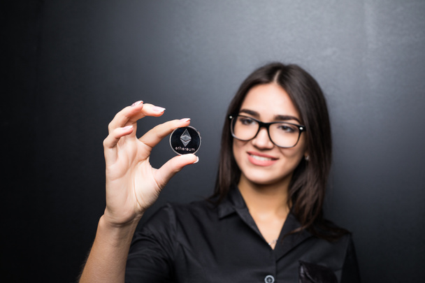 Joven mujer de negocios en gafas con Litecoin en manos aisladas sobre fondo negro
. - Foto, Imagen