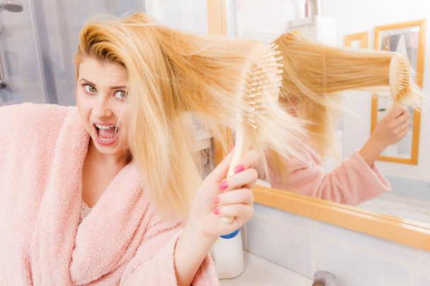 Shocked woman wearing dressing gown brushing her hair - 写真・画像