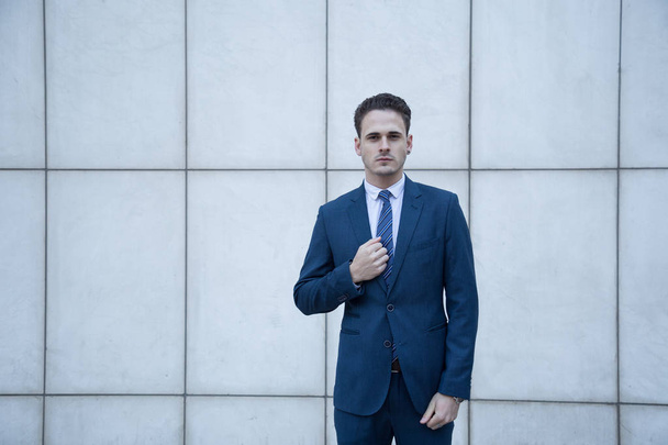 Young business man dressed in suit on a white background with lines of a building. - Foto, Bild