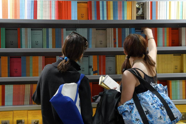 Women back view picking books from shelves in a book fair Turin Italy circa May 2015 - Foto, Imagem