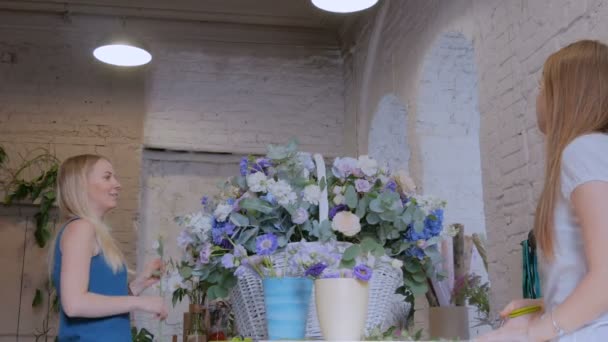 Zwei Floristinnen basteln im Blumenladen einen großen Blumenkorb mit Blumen - Filmmaterial, Video