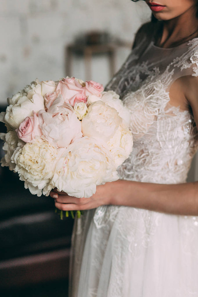 Beautiful bridal bouquet of bride from white peonies and roses in the hands of the bride - Photo, image