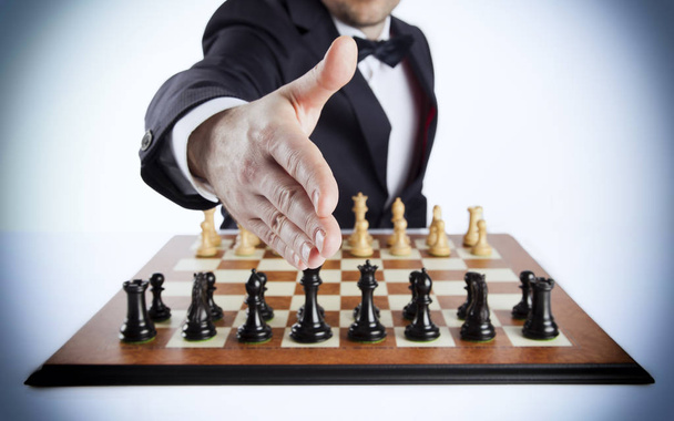 Un hombre inteligente con un traje oscuro sobre el tablero de ajedrez vacío desafiándote
!  - Foto, Imagen