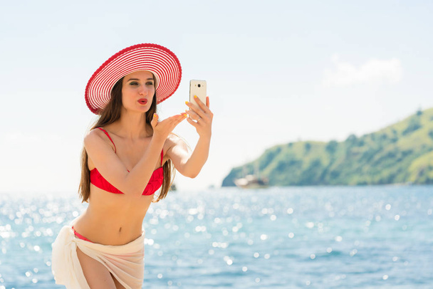 Young woman blowing a kiss while sharing on social media live video in Flores Island, Indonesia - Photo, Image