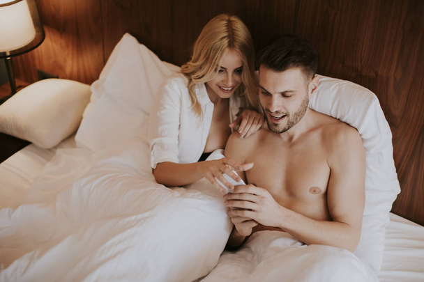 Szerető és ölelkező pár az ágyon a szobában - Fotó, kép