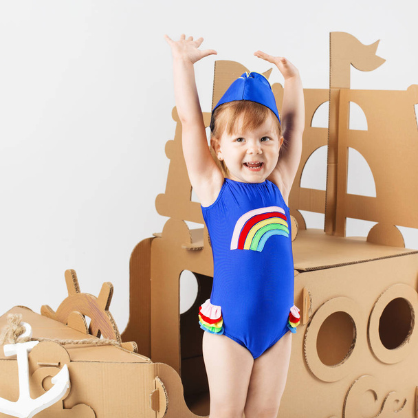 Petite fille mignonne portant un maillot de bain lumineux jouant avec du carton
  - Photo, image