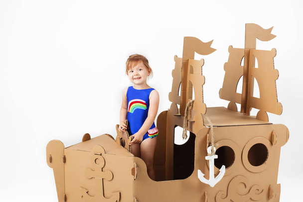 Cute Little girl wearing bright swimsuit playing with cardboard  - Photo, Image