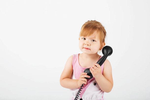маленькая девочка с ретро-телефоном против белого
 - Фото, изображение