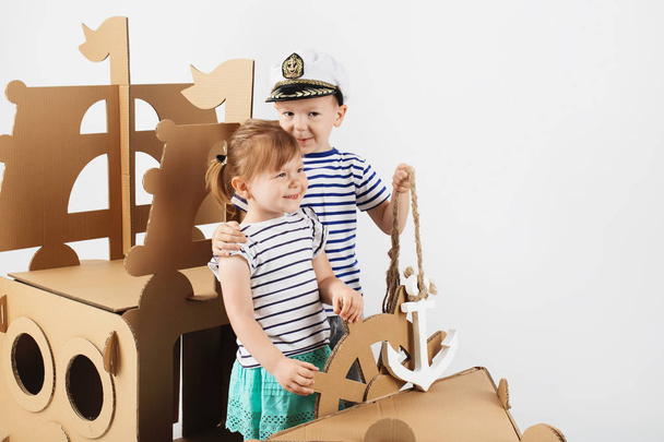 Little kids playing with cardboard ship on white background. Hap - Photo, Image