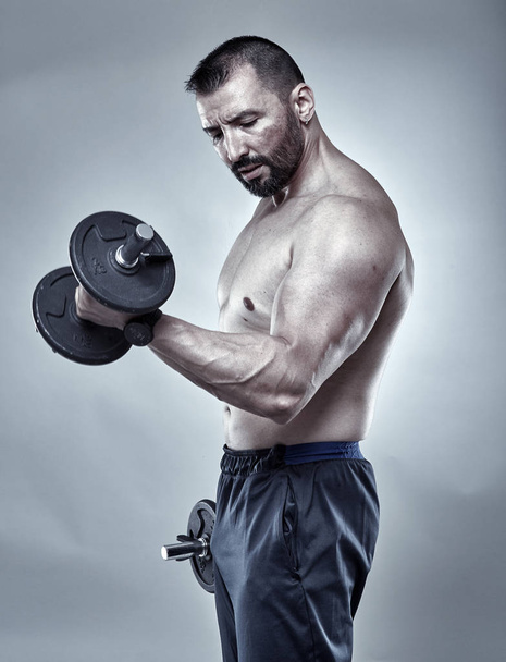 Mature fit man working with dumbbells - Foto, afbeelding