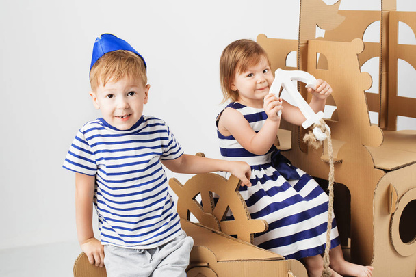 Маленькі діти грають з картонним кораблем на білому тлі. Щасливий
 - Фото, зображення