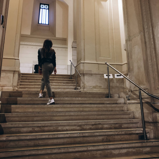 vista da jovem mulher nas escadas do edifício antigo na cidade
 - Foto, Imagem