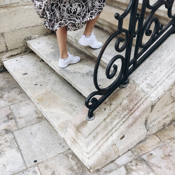Vista recortada de las piernas femeninas subiendo las escaleras con valla metálica decorada
. - Foto, imagen