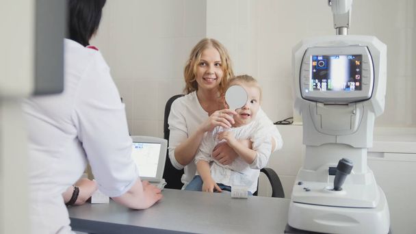 Optometrist checks childs eyesight - mother and child in ophthalmologist room - Photo, Image