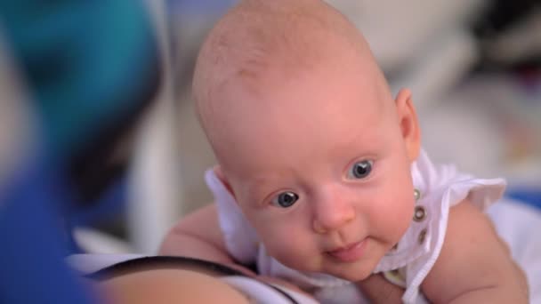 Baby hebt den Kopf und schaut mit großen blauen Augen - Filmmaterial, Video