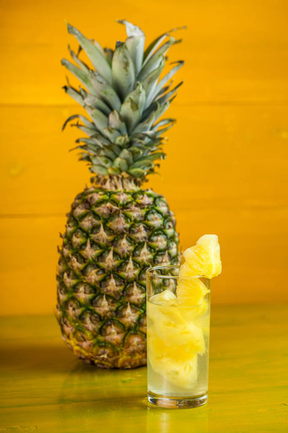 Piña madura y jugo en un vaso sobre un fondo de madera amarilla
 - Foto, imagen