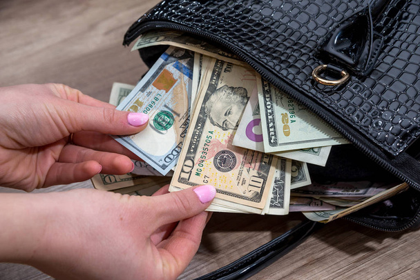 Mädchen ziehen Dollar aus den prall gefüllten Geldbeutel. - Foto, Bild