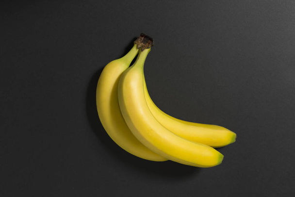 Three bananas on a black background. - Фото, изображение