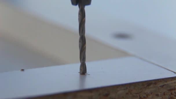 Makró. Közelről. A bútorok mester pierces a lyuk egy fúróval a fehér forgácslap. - Felvétel, videó