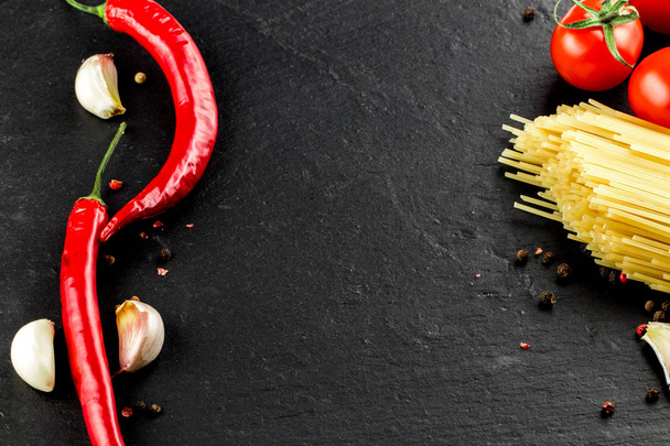 Italian cuisine. Vegetables,  spices and pasta on dark backgroun - Photo, Image