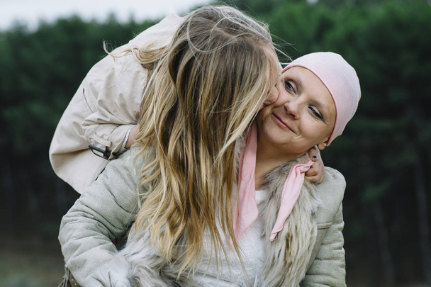 A woman with cancer is  next to her daughter. A girl is hugging  - Photo, Image