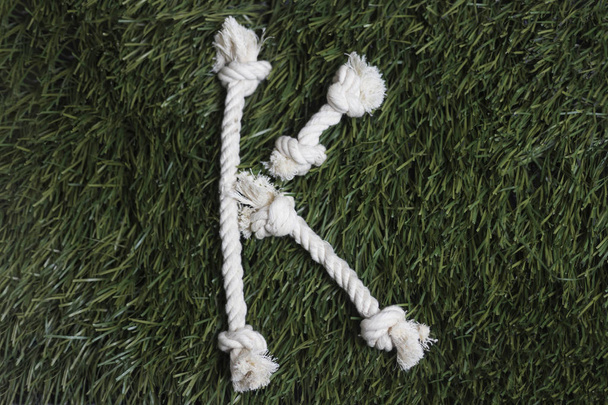 Alfabeto de cuerda sobre hierba. Letra K
 - Foto, imagen